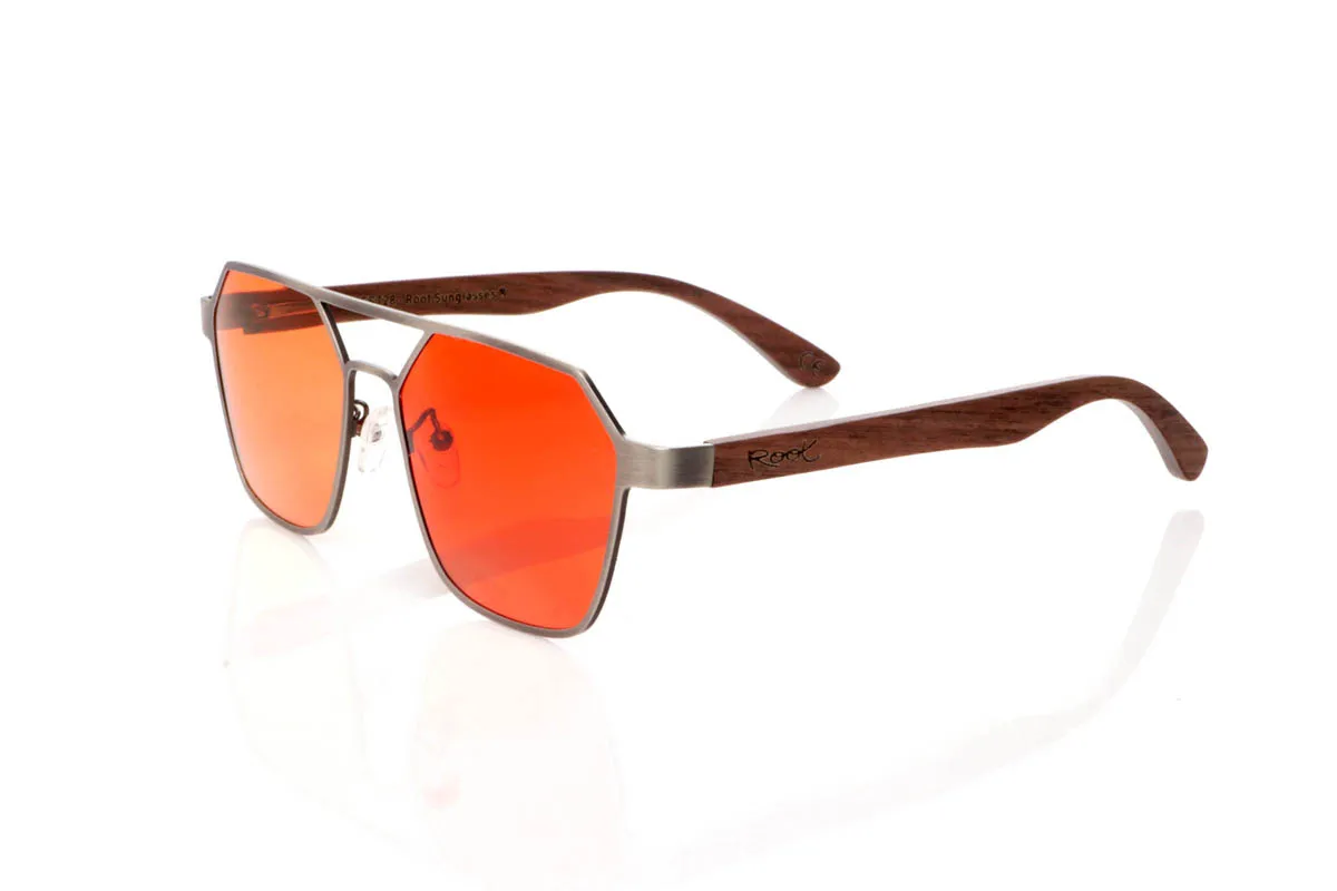 Gafas de Madera Natural de Walnut modelo IBON. Las gafas de sol <b>IBON</b> combinan un frontal metálico de líneas geométricas con varillas de madera de walnut, creando una mezcla sofisticada entre diseño moderno y calidez natural. Su forma angular, con doble puente abierto y estructura ligera al aire, aporta un estilo atrevido y muy actual, ideal para quienes buscan unas gafas con presencia sin resultar pesadas. Las varillas de madera, finas y curvadas, muestran vetas naturales que hacen que cada par sea único y aportan comodidad durante el uso diario. Equipadas con lentes polarizadas que reducen los reflejos y protegen eficazmente frente a los rayos UV, son unas gafas diferentes, elegantes y con carácter propio. Medidas: 145x50 mm. Calibre 54. | Root Sunglasses® 
